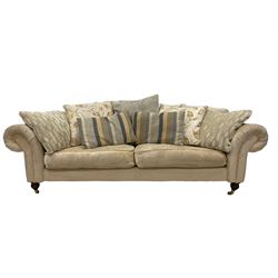 DFS - three seater sofa, upholstered in cream fabric, raised on turned and reeded supports, terminating in brass castors 
