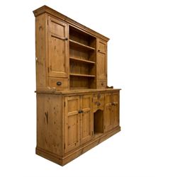 20th century pine dresser, projecting cornice over three central plate racks flanked by two cupboards and drawers, the lower section fitted with two drawers and two double cupboards with panelled doors, raised on plinth base