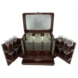 Edwardian mahogany decanter box, the mahogany banding strung with ebony, the hinged cover with internal mirror inset, set over two hinged doors enclosing a  fitted interior with three later glass decanters and drinking glasses and single drawer fitted to base, H33.5cm, W35cm, D25cm