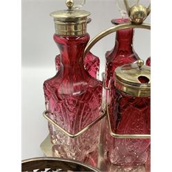 Early 20th century silver-plated cruet set with six cranberry glass bottles, together with a pair of silver-plated bottle coasters (3)