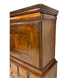 Early 18th century walnut escritoire, the projecting moulded cornice over a cushion frieze drawer, the banded fall-front with concentric feather stringing and inset red leather writing surface to the interior, enclosing a fitted interior comprising nine pigeonholes concealing three secret drawers over an assortment of eleven small drawers surrounding a central cupboard, the base with two short over two long feather-strung graduating drawers on later bracket feet
Provenance: From the Estate of the late Dowager Lady St Oswald