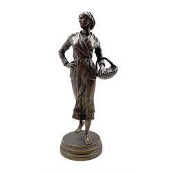 Ernest Charles Guilbert (French, 1815 -1865): Bronze standing figure of a girl holding a basket on circular base, H58cm
