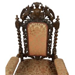 Pair of Victorian Jacobean Revival heavily carved oak armchairs, the pediment with central cartouche flanked by pierced and carved griffon motifs, the padded back surrounded by oak and scrolling acanthus leaves with flanking spiral turned uprights, back and sprung seat upholstered in red and gold urn patterned fabric, the arm terminals in the form of dog masks, on barley-twist supports united by spiral turned stretchers