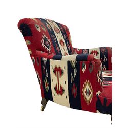 Howard & Sons Ltd - late 19th century easy armchair, upholstered in kilim fabric with sprung back and seat, raised on ring turned tapering supports with brass cups and castors, the rear leg stamped '12332 9522 Howard & Sons Ltd Berners Street', each castor stamped 'Howard & Sons Ltd London'