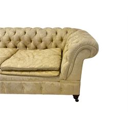 Early 20th century mahogany framed Chesterfield sofa, scrolled drop-arms, upholstered in light gold buttoned Damask floral pattern fabric with sprung seat, raised on turned feet with castors
