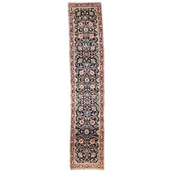 Persian crimson ground runner rug, the indigo field decorated with intertwining and scrolling foliate patterns with palmettes, the guarded border with repeating flower and plant motifs