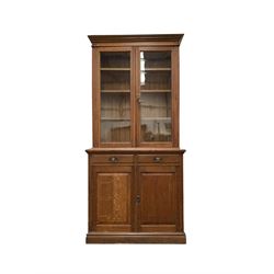 Edwardian oak bookcase on cupboard, two glazed doors enclosing three adjustable shelves, two drawers and two panelled cupboard doors under, bearing ivorine makers label reading 'Holliday, Son & Co. Ltd. Birmingham' W107cm, H228cm, D50cm
