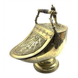 Victorian brass helmet shaped coal scuttle having embossed decoration with turned wooden handle and shovel, H49cm