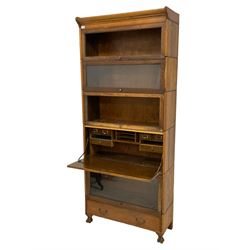 Early to mid-20th century five sectional stacking library bookcase, four sections with hinged sliding doors, one section with fall front enclosing fitted interior, and lower drawer to base, raised on carved paw feet