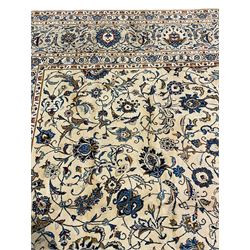 Large Persian Kashan ivory ground carpet, decorated all-over with interlacing branch and stylised flower heads, repeating scrolling border with plant motifs, triple guard bands