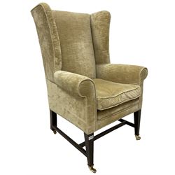 19th century wingback armchair upholstered in ivory fabric, raised on square tapering supports, terminating in brass castors 