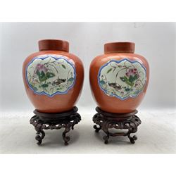 Pair of 19th century Chinese porcelain burnt orange ground ginger jars and covers, each having two reserves enamelled with pair of mandarin ducks swimming in a lotus pond and birds perched amongst flowering branches to the reverse, on hardwood stands H25cm 
