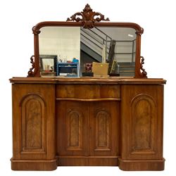 Victorian mahogany mirror back sideboard, carved applied cartouche pediment with extending foliate scrolls over the rectangular mirror plate, fitted with central serpentine cushion drawer over double cupboard with moulded arched panels, flanked by two single cupboards enclosing drawers, sliding trays and shelves