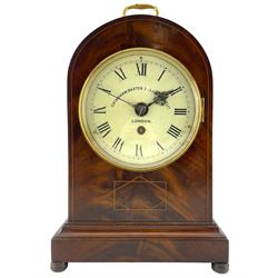Grimshaw Baxter & Elliot of London – Edwardian single train 8-day fusee mahogany mantle clock, with a round top on a rectangular plinth raised on round feet,
painted dial with Roman numerals and minute track, 18th century style fretted steel hands within a glazed bezel, chain driven fusee movement with a recoil anchor escapement and pendulum lock. With pendulum and key
