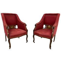Pair Edwardian walnut framed armchairs, upholstered in crimson fabric with sprung seat, the central back panel pierced and inlaid with foliate motifs, raised on cabriole supports with castors
