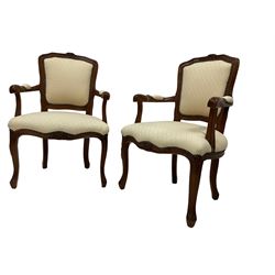 Pair Louis XVI design walnut framed salon armchairs, the cresting rail decorated with moulded flowerheads and extending fluting, scrolled arm terminals, raised on cabriole supports, upholstered in ivory patterned fabric with studwork, 