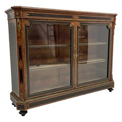 Victorian ebonised and amboyna wood credenza pier cabinet, rectangular moulded top with extending canted corners, mounted throughout with gilt metal beading, the frieze with ebonised panels and central inlaid scrolling and interlaced cartouche, enclosed by two glazed doors with inlaid upper spandrels, the canted uprights mounted with gilt metal lion masks on torches with foliate swags over matching inlays and lower acanthus leaf mount, the skirted base with foliate moulded band and ebonised inlaid panels, on turned feet