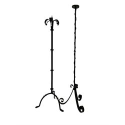 Late 19th century wrought iron floor standing candlestick or torchere, the pricket surrounded by a lily design top, raised on a turned column terminating in a tripod base, together with another similar (2)