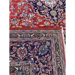 Large Persian red ground carpet, blue and ivory floral medallion on busy red field, with stylised foliate to triple guarded border 390cm x 294cm