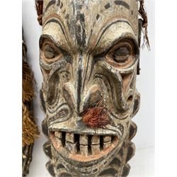  Papua New Guinea Sepik River mask of elongated oval form, brown and white pigment and cowrie shells 49cm x 28cm and another with black, orange, pink and white pigment 46cm x 15cm