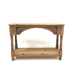 Victorian style pine side table, rectangular moulded top over arched apron carved with acorns and oak leaves, raised on turned supports united by under tier 