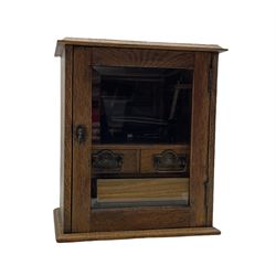 Early 20th century oak smokers cabinet with glazed hinged door enclosing two drawers and removable pipe rack in the form of a gate, with various pipes and smoking paraphernalia, H34cm, D19cm, W29cm