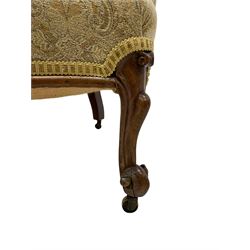 19th century rosewood framed armchair, curved back and arms upholstered in buttoned floral pattern fabric, foliate carved apron and cabriole feet with scroll carved terminals, on brass castors