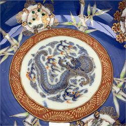 Set of four Japanese graduating porcelain bowls, each centrally painted with a coiled dragon in reserves, bamboo and foliate roundels against a blue ground, largest measuring D24.5cm (4)