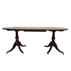 Regency design twin pillar dining table, 19th century and later, the oval top with reeded edge and one additional leaf over turned columns and splayed supports terminating in brass cup castors 