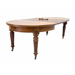 Edwardian mahogany oval wind out extending dining table, with floral carved roundels, raised on turned tapered and fluted supports terminating in brass and ceramic castors, with two additional leaves and winding handle 240cm x 120cm, H75cm