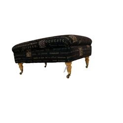 20th century footstool, upholstered in fabric with Latin text and illuminated letters, raised on turned feet with brass castors 