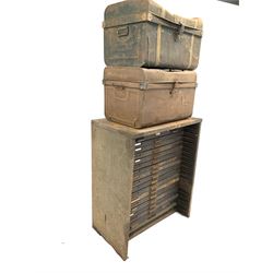 Early 20th century printers cabinet, sheet metal frame fitted with nineteen stained pine drawers with divisions for printing blocks of various sizes, one drawer missing, (W90cm, H108cm, D54cm)together with two dome top tin trunks (70cm) 