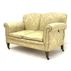 Early 20th century two seat settee with drop end, upholstered in pale gold Damask fabric, square tapering feet with brass and ceramic castors, W138cm