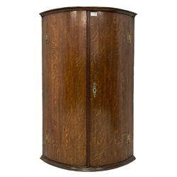 Early 19th century oak bow fronted corner wall cupboard, two doors enclosing three shelves