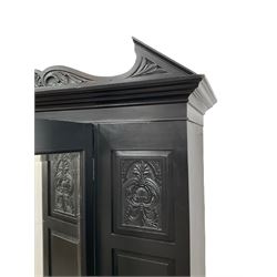 19th century black painted wardrobe, the pointed and scroll carved pediment over panelled and carved front with central bevelled mirror door, drawer to base, on bracket feet