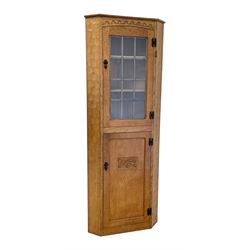 'Gnomeman' adzed oak corner cupboard, the top section enclosed by lead glazed door, the lower section enclosed by panelled door carved with mythical dragon, fitted with shelves, carved with gnome signature, by Thomas Whittaker of Little Beck, W70cm, H184cm, D45cm