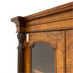 Victorian figured walnut enclosed bookcase, projecting cavetto cornice over two tall glazed doors, fitted with adjustable shelves, turned and fluted upright pilasters with lappet and guilloche carved decoration, on plinth base