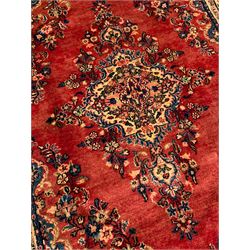 Persian crimson ground rug, the field with shaped central medallion and surrounding floral decoration, multiple band border, the main band decorated with repeating floral bouquets and trailing leafy branches