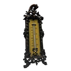 Early 20th century desk thermometer by Franks, Deangate, Machester, with ivorine panel and ornate cast iron frame, surmounted by a Cherub mask, on scroll supports, H32cm