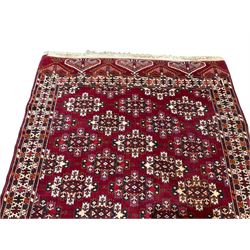 Anatolian crimson ground rug, field decorated with all-over uniform geometric Gul motifs, the multi-band border with repeating hexagonal designs, with repeating Elibelinde motifs