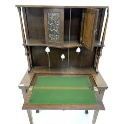 Early 20th century oak Arts and Crafts writing desk, raised back with open shelf and cupboard to centre with hammered brass panels over a fold out baize lined writing surface and single drawer, raised on square tapered supports