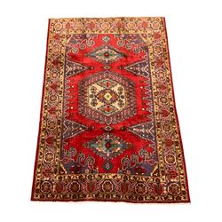 Persian red ground rug, the field decorated with stepped lozenges and central medallion, guarded border with stylised flower head motifs 