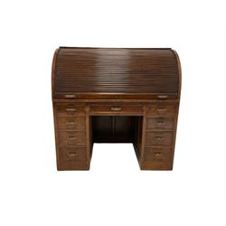 20th century mahogany desk, the roll top opening to reveal interior with drawers, pigeon holes and pull our writing surface over nine drawers, raised on recessed castors W123cm, H127cm, D71cm 