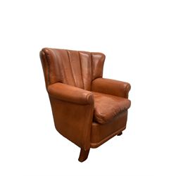 Club armchair upholstered in tan leather, barrel back and rolled arms, with stud work detail, on splayed feet
