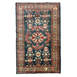 Persian indigo ground rug, the central crimson medallion with extending patterns, surrounded by geometric floral designs, guarded border with repeating decoration