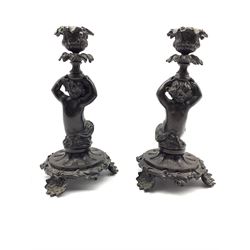 Pair of patinated bronze figural candlesticks, each in the form as a seated Cherub, supporting a fruit cast nozzle, H21.5cm 