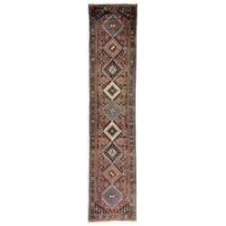 Persian Yalameh terracotta ground runner rug, the field decorated with a column of intricate geometric lozenges with interior star and hook motifs, the surrounded busy field filled with stylised floral patterns and flower heads, the guard band with further repeating lozenges