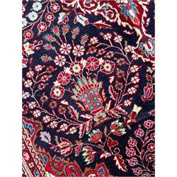 Persian Qom blue ground rug, the field decorated with central scrolling medallion surrounded by eight floral urns and stylised plant motifs, floral decorated spandrels and repeating guarded border