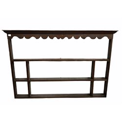 Early 19th century country oak plate rack, cornice over shaped apron and three tiers, W178cm