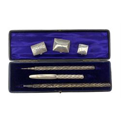 Writing set comprising pen, pencil and nib cutter with spiral stems in fitted case, the nib cutter hallmarked for London 1891 Maker Sampson Mordan & Co, the two other items not marked, retailed by Frank Smythson, 133 New Bond St. and three small silver boxes, one inset with a seed pearl flower head.  Provenance:  From the Estate of the late Dowager Lady St Oswald